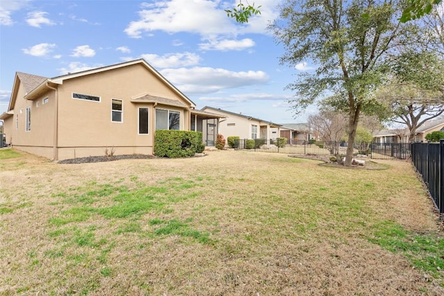 back of property featuring stucco siding, a lawn, and a fenced backyard