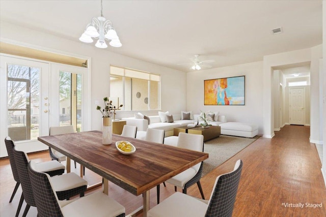 dining space featuring visible vents, baseboards, light wood-style flooring, french doors, and ceiling fan with notable chandelier