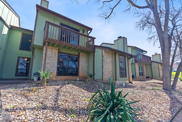 exterior space with stone siding and a balcony