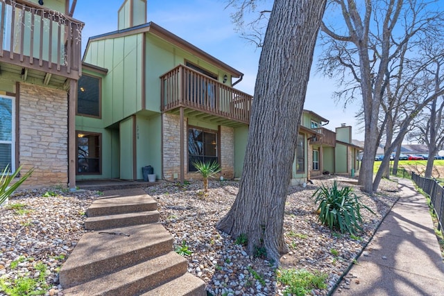 exterior space with board and batten siding, stone siding, and a balcony