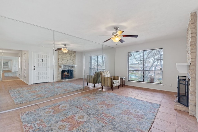 unfurnished room featuring tile patterned flooring, a large fireplace, ceiling fan, and baseboards