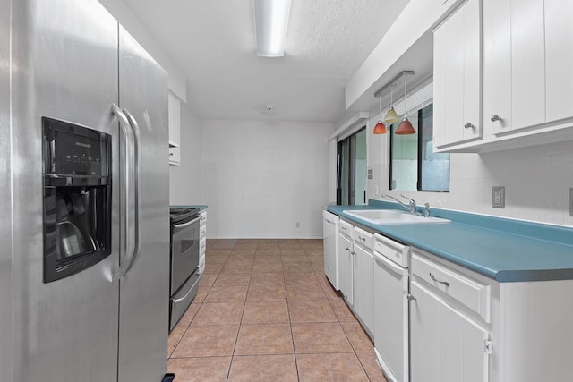 kitchen with white cabinets, appliances with stainless steel finishes, a sink, backsplash, and light tile patterned flooring