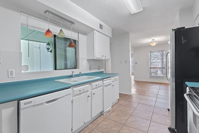 kitchen with light tile patterned floors, stainless steel appliances, visible vents, decorative backsplash, and a sink