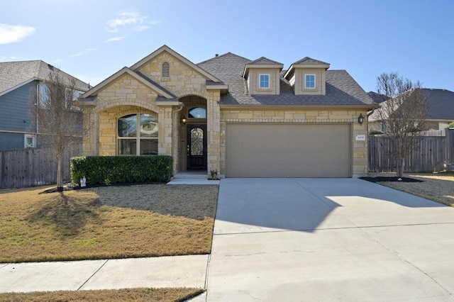 view of front facade with driveway, an attached garage, fence, and a shingled roof