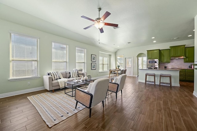 living area with dark wood-style floors, arched walkways, baseboards, and recessed lighting