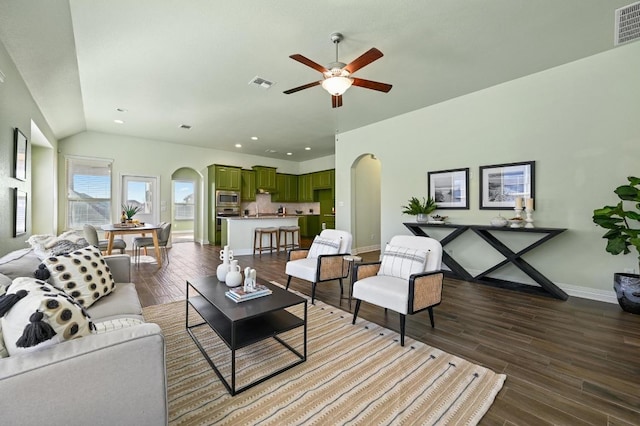 living area with arched walkways, vaulted ceiling, wood finished floors, and visible vents