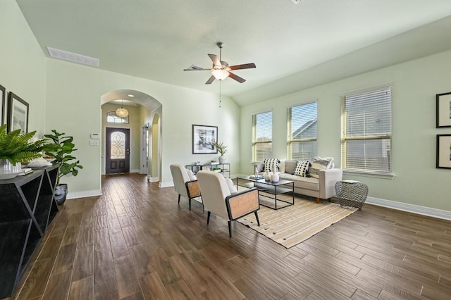 living area with arched walkways, dark wood finished floors, visible vents, and baseboards