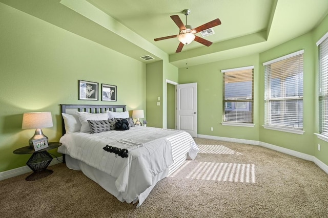 unfurnished bedroom with carpet floors, a ceiling fan, visible vents, baseboards, and a raised ceiling