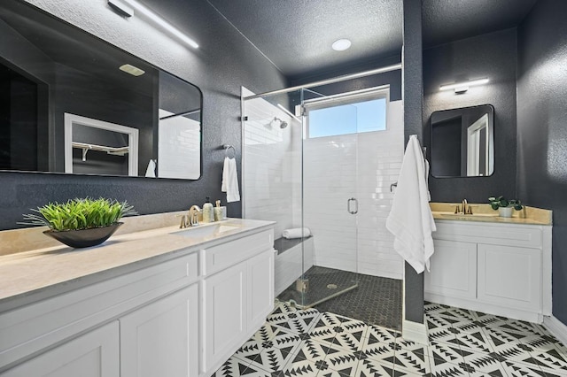 bathroom featuring a textured wall, a stall shower, vanity, a textured ceiling, and tile patterned flooring