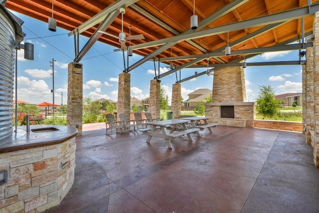 view of patio featuring outdoor dining space, an outdoor stone fireplace, and a ceiling fan