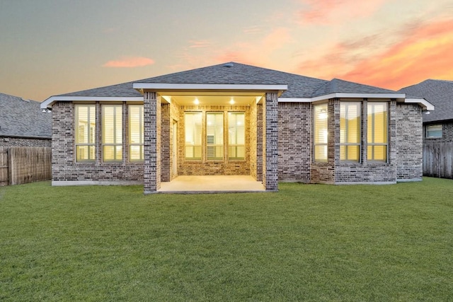 rear view of house with a fenced backyard, a yard, brick siding, and a patio