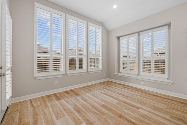 spare room featuring lofted ceiling, light wood finished floors, baseboards, and recessed lighting