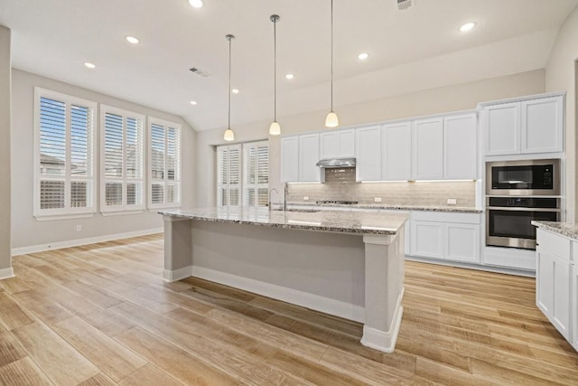 kitchen with tasteful backsplash, white cabinets, stainless steel appliances, light wood-type flooring, and a sink