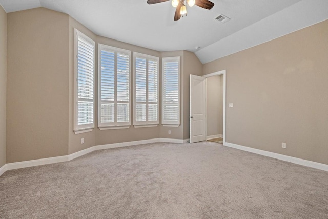 spare room featuring baseboards, visible vents, light colored carpet, ceiling fan, and vaulted ceiling