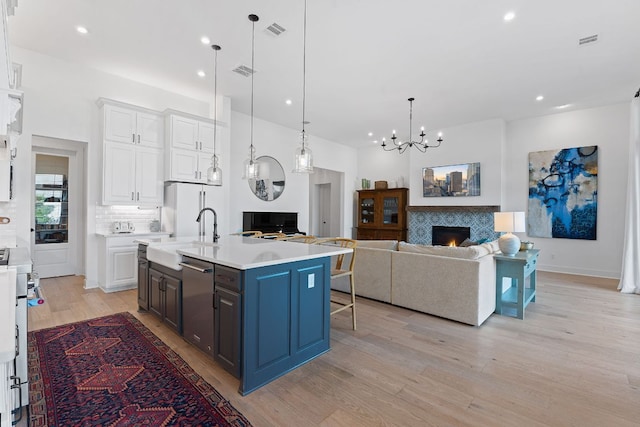 kitchen featuring visible vents, a tile fireplace, a sink, light countertops, and white cabinets