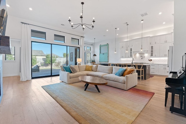 living area with a notable chandelier, visible vents, light wood-style flooring, and recessed lighting