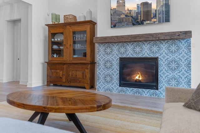 living area featuring a city view, a tile fireplace, baseboards, and wood finished floors