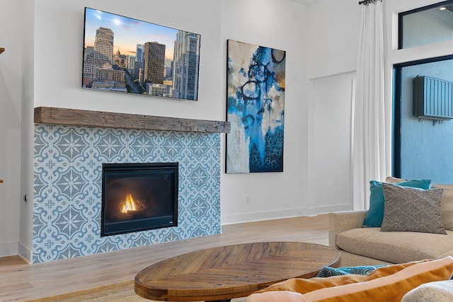 living room featuring wood finished floors, baseboards, and a tile fireplace