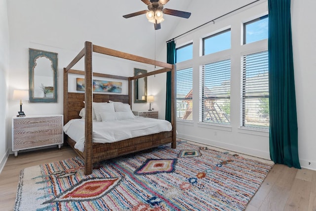 bedroom featuring light wood-style flooring, multiple windows, baseboards, and high vaulted ceiling