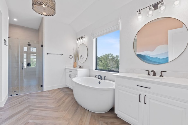 full bathroom with baseboards, a soaking tub, two vanities, a stall shower, and a sink