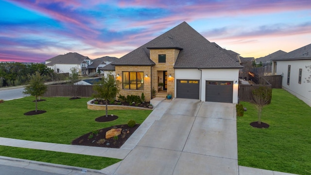 french provincial home featuring a front lawn, an attached garage, fence, and stone siding