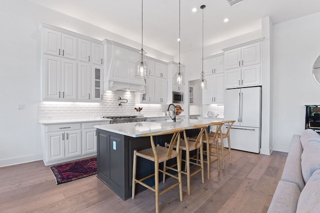 kitchen featuring light wood-style flooring, freestanding refrigerator, light countertops, white cabinetry, and stainless steel microwave