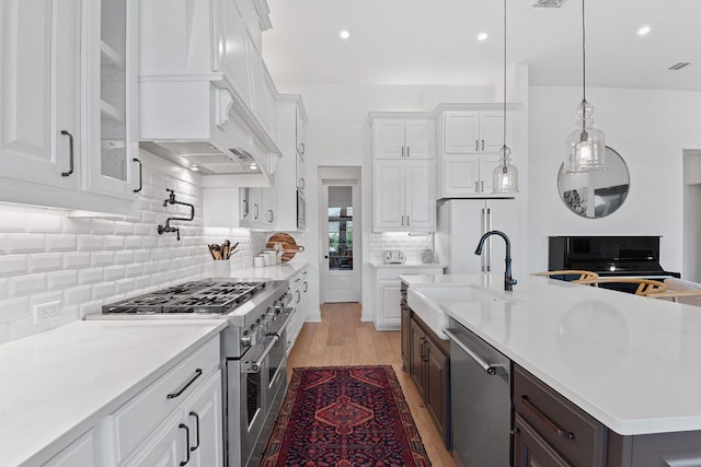 kitchen featuring custom range hood, a sink, white cabinetry, stainless steel appliances, and light countertops