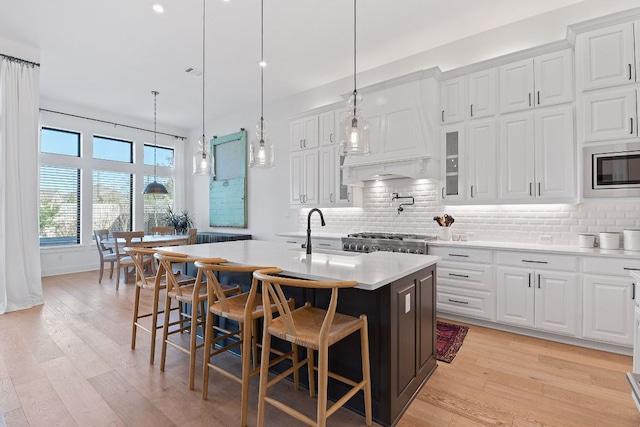 kitchen with tasteful backsplash, light wood finished floors, light countertops, stainless steel appliances, and a sink