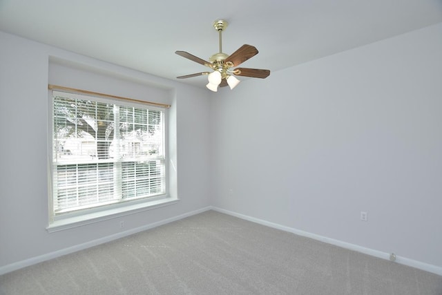 spare room with light carpet, a ceiling fan, and baseboards