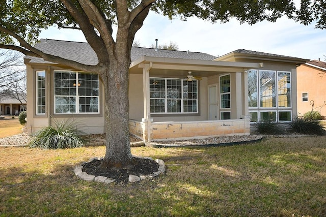 exterior space with a ceiling fan, roof with shingles, a yard, and stucco siding