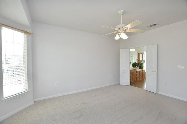 empty room with light carpet, visible vents, and a wealth of natural light