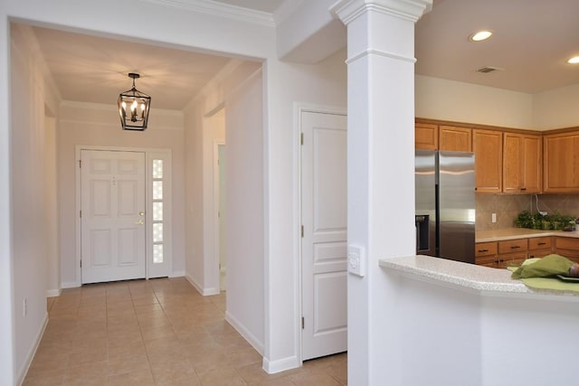 foyer entrance with light tile patterned floors, decorative columns, crown molding, and recessed lighting