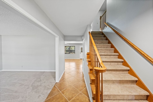 stairs featuring carpet, baseboards, a textured ceiling, and tile patterned floors