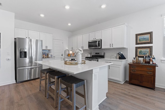 kitchen featuring stainless steel appliances, white cabinets, and wood finished floors