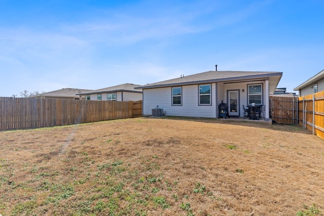 rear view of property with central AC, a lawn, and a fenced backyard