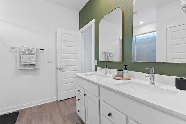 bathroom featuring double vanity, a sink, baseboards, and wood finished floors