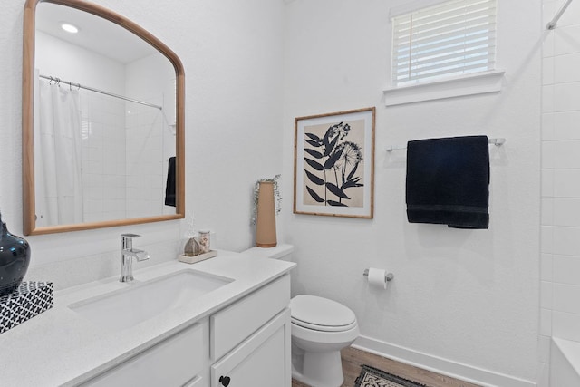 bathroom with curtained shower, toilet, wood finished floors, vanity, and baseboards