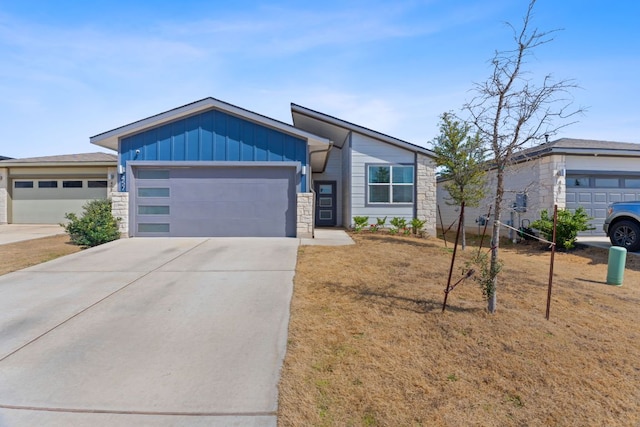 view of front facade featuring a garage, driveway, board and batten siding, and stone siding