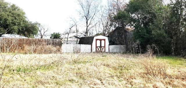 view of yard featuring an outbuilding, a storage unit, and fence