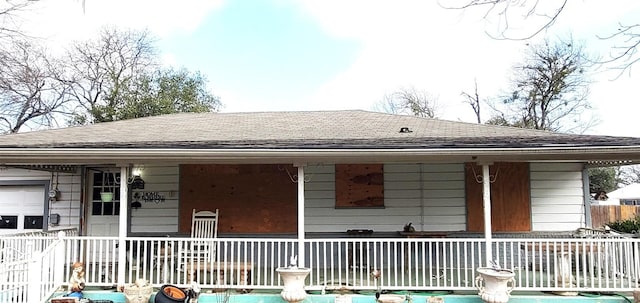 exterior space with a porch, a shingled roof, and fence