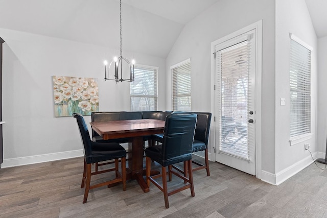 dining room with lofted ceiling, baseboards, a notable chandelier, and wood finished floors