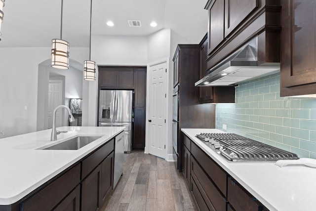 kitchen with stainless steel appliances, visible vents, a sink, dark brown cabinetry, and under cabinet range hood