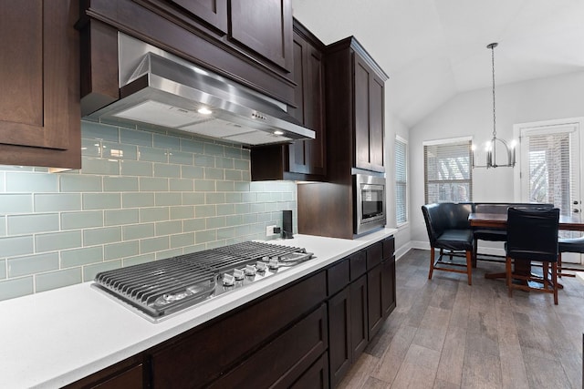 kitchen featuring dark brown cabinetry, light countertops, appliances with stainless steel finishes, ventilation hood, and backsplash