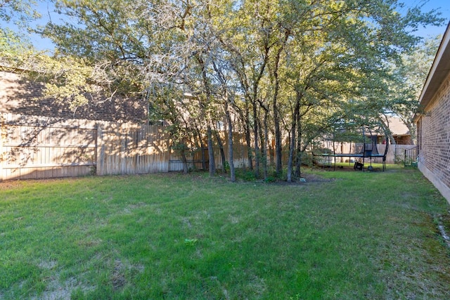 view of yard featuring a trampoline and a fenced backyard