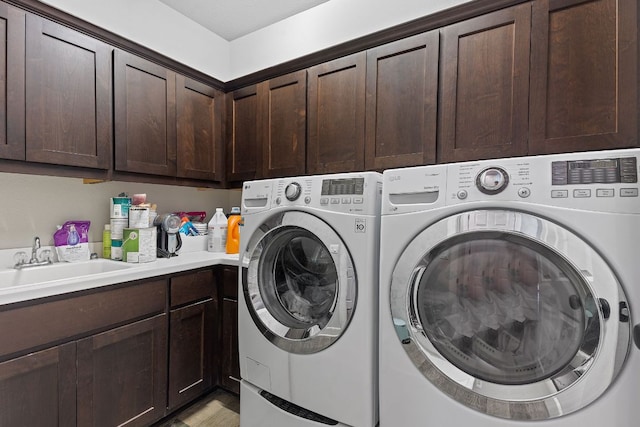 clothes washing area featuring washer and dryer, cabinet space, and a sink