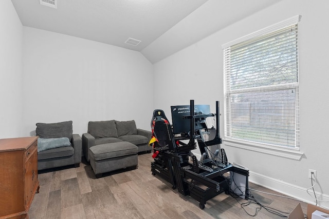 workout area featuring lofted ceiling, visible vents, baseboards, and wood finished floors