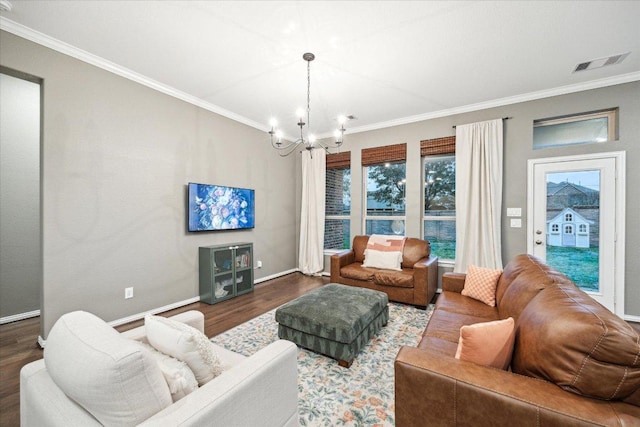 living room featuring a notable chandelier, visible vents, ornamental molding, wood finished floors, and baseboards