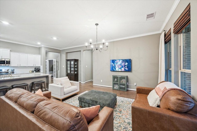 living room with ornamental molding, wood finished floors, visible vents, and baseboards