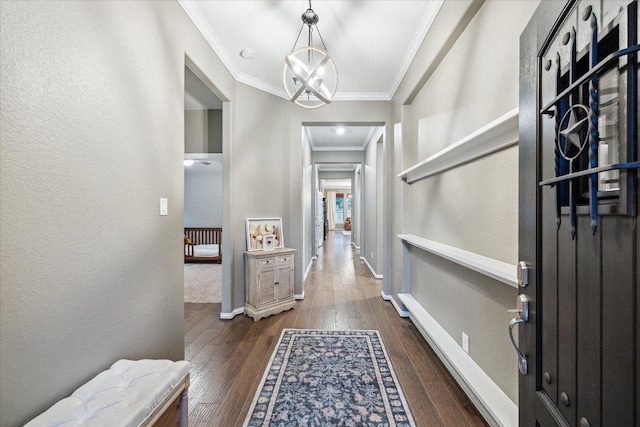 hall with dark wood-style floors, ornamental molding, baseboards, and an inviting chandelier