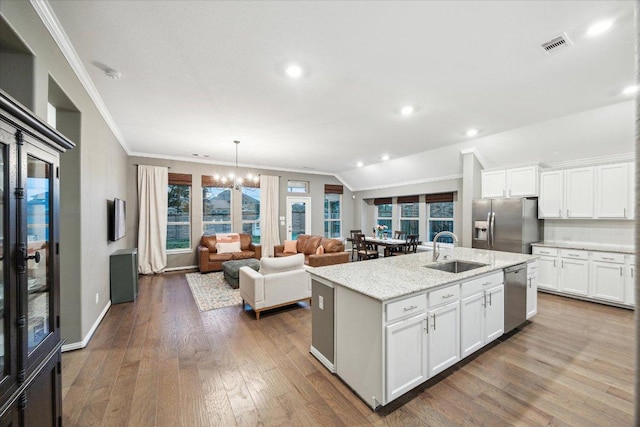 kitchen featuring stainless steel appliances, wood finished floors, a sink, white cabinetry, and crown molding